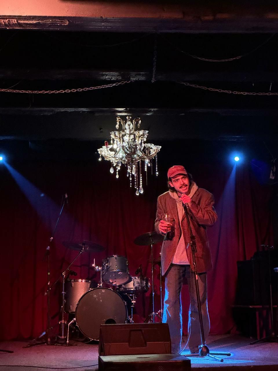 Selah Ucla performing under a chandelier on a bar stage